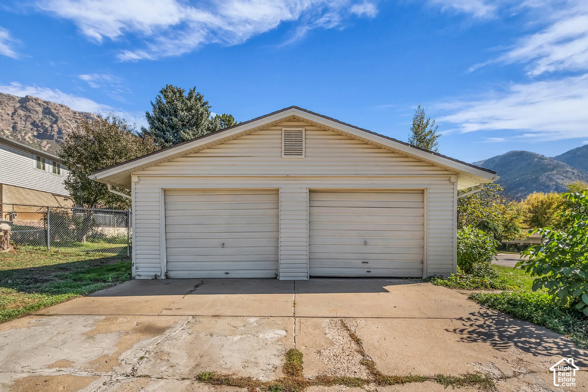 Detached two-car garage featuring horizontal siding, a gable roofline, and a concrete driveway, set against a backdrop of mountain scenery