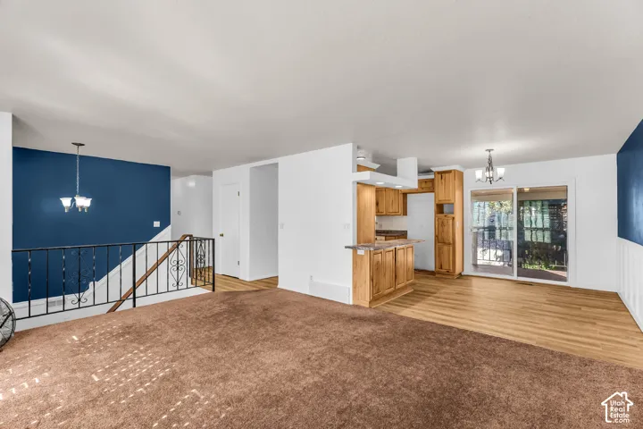 Open-concept interior featuring wood-finish cabinetry, hard surface flooring, decorative metal stair railing, and sliding glass doors