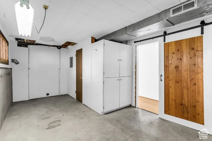 Interior space featuring concrete flooring, built-in white cabinetry, and a sliding barn-style door with wood paneling