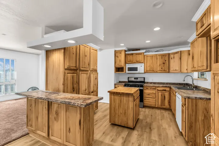 Kitchen featuring natural wood cabinetry, stone-pattern laminate countertops, wood-finish flooring, a mobile center island, and recessed ceiling lighting