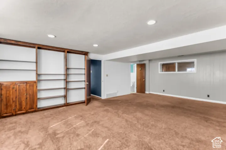 Built-in wood shelving unit, recessed lighting, wall-to-wall carpeting, and horizontal sliding window