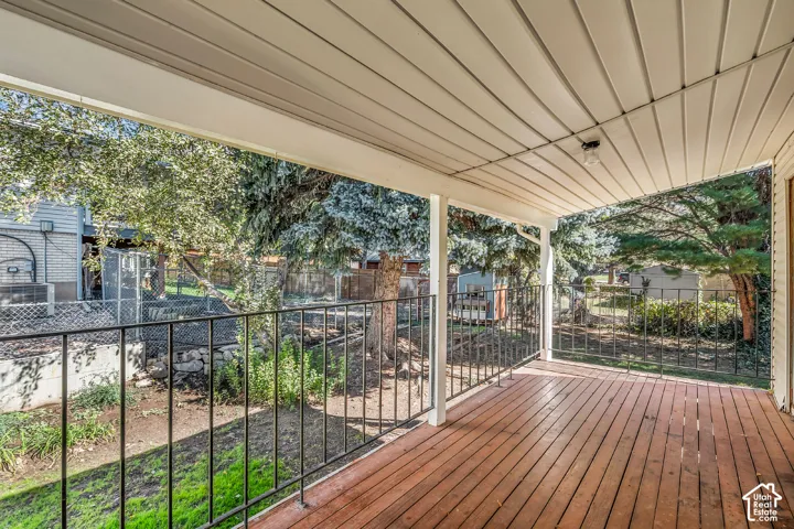 Covered deck featuring wood-plank flooring, metal railings, and a solid ceiling panel finish