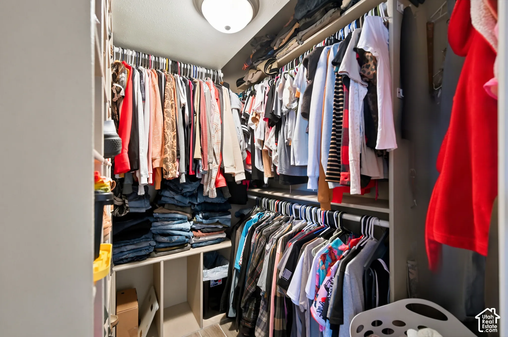 Walk-in closet featuring tiered clothing rods, built-in shelving units, and a ceiling-mounted light fixture