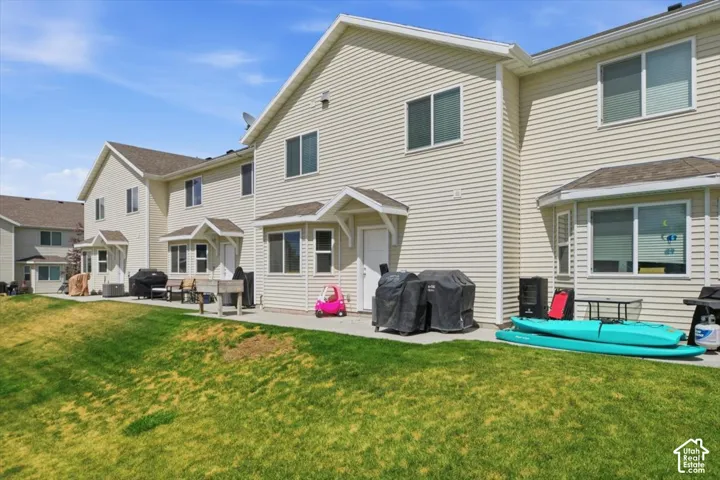 Multi-family exterior featuring light-colored horizontal siding, dual-pitched roof gables, concrete rear patios.
