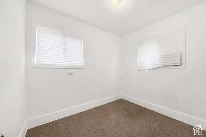 Interior room featuring neutral wall-to-wall carpeting, two dual-pane windows, and white window shades