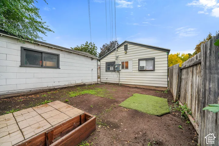 Exterior space featuring horizontal siding, a detached structure with block-wall construction, a wood-frame garden bed, and wood fencing