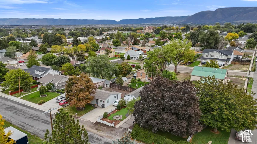 Aerial perspective featuring a residential setting with mature trees and a mountain backdrop
