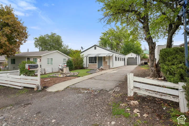 Single-story exterior featuring white horizontal siding, a detached garage, metal window awnings, and a concrete driveway
