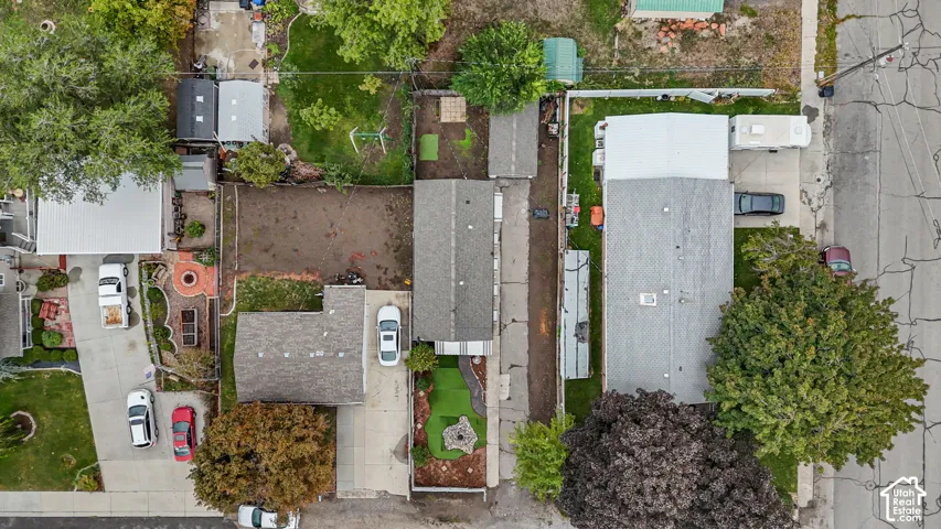 Aerial perspective featuring an asphalt driveway, paved walkways, artificial turf areas, and established perimeter fencing