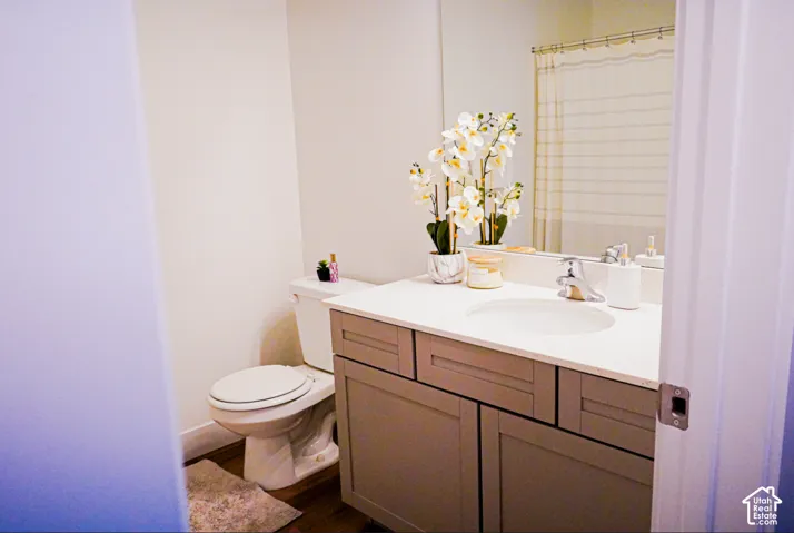 Bathroom featuring a vanity with neutral-toned cabinetry, a solid-surface countertop, an integrated sink, a polished metal faucet, and a wall-to-wall mirror