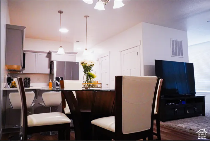 Kitchen featuring grey cabinetry, stainless steel appliances, and pendant lighting over a peninsula counter