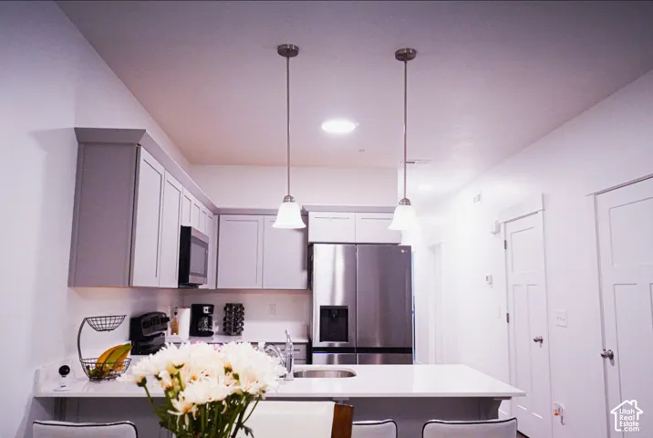 Kitchen featuring light-toned cabinetry, stainless steel appliances, quartz countertops, and dual pendant lighting fixtures