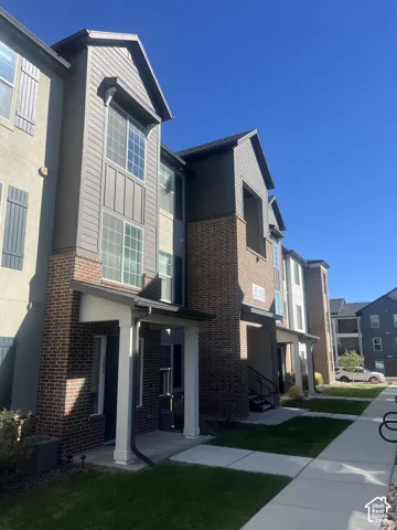 Multi-story exterior featuring a combination of brick masonry and horizontal siding, decorative shutters, gabled rooflines, and covered entryways