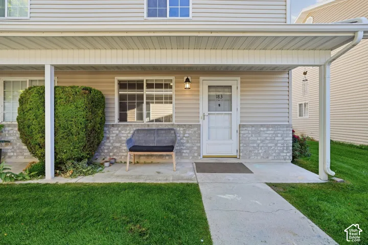 Exterior featuring horizontal vinyl siding, a light-toned stone veneer lower facade, covered concrete front porch, and an exterior wall-mounted light fixture