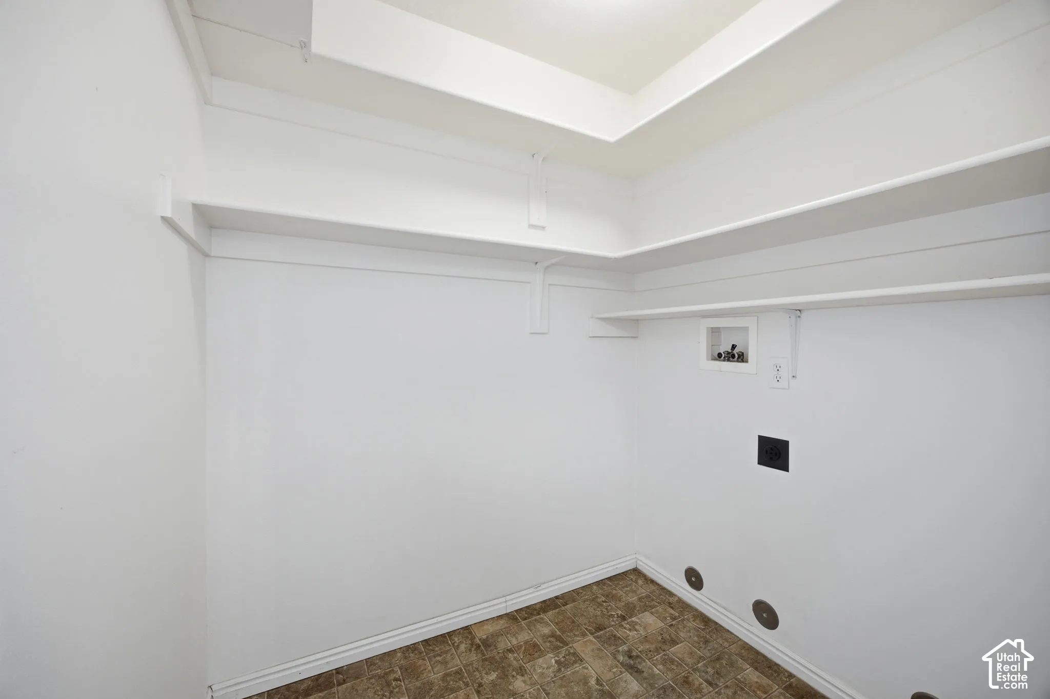 Dedicated utility area featuring white walls, tiered built-in shelving, vinyl flooring, and integrated appliance hookups