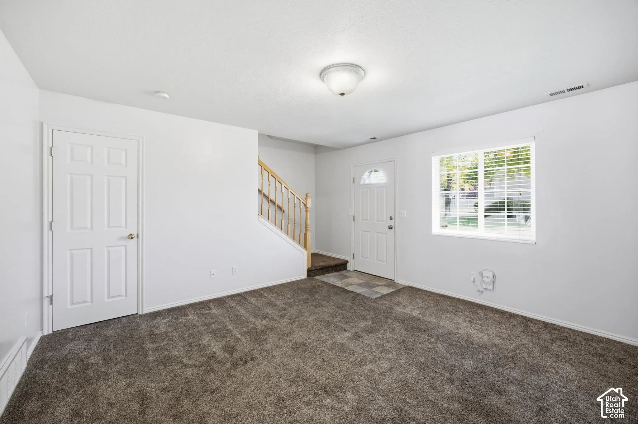 Interior space featuring wall-to-wall carpeting, a multi-lite glass panel entry door, and a staircase with wood handrailing