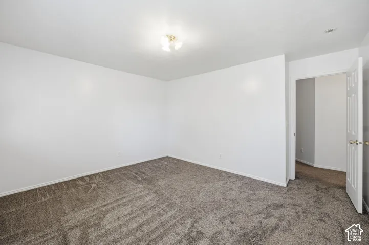 Neutral wall paint, textured carpeting, multi-bulb ceiling fixture, and a six-panel interior door
