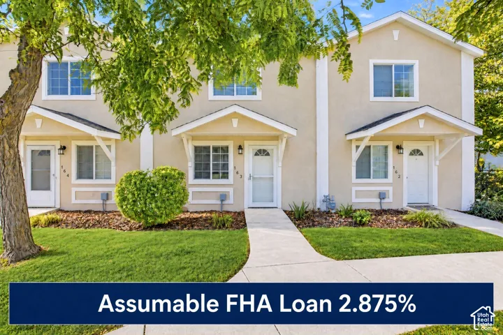Multi-unit exterior featuring a smooth stucco facade, gabled entryway covers, grid-pattern windows, and individual white entry doors