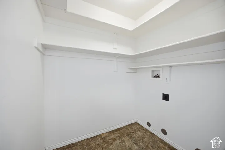 Dedicated utility area featuring white walls, tiered built-in shelving, vinyl flooring, and integrated appliance hookups