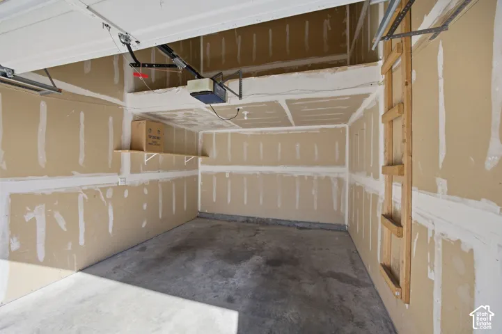 Garage featuring unfinished drywall, built-in wooden shelving, a fixed wooden ladder, and elevated storage platform