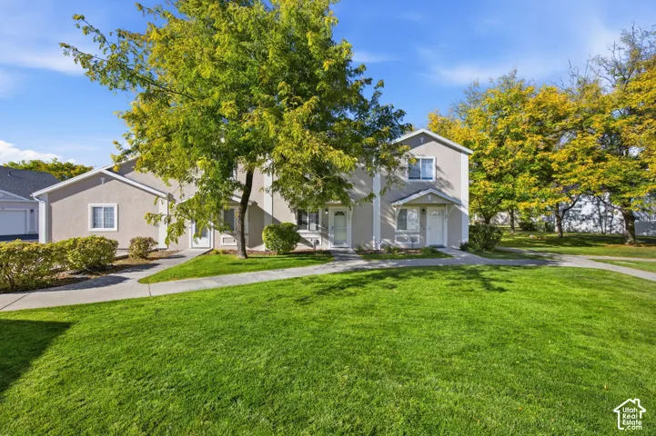 Stucco exterior featuring multi-level architecture, concrete walkways, and established landscaping with mature trees