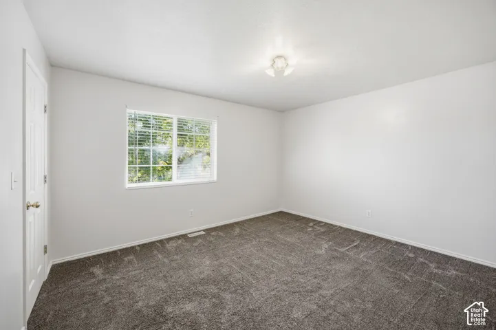 Neutral wall finishes, plush carpeting, multi-pane sliding window, and flush-mount ceiling light