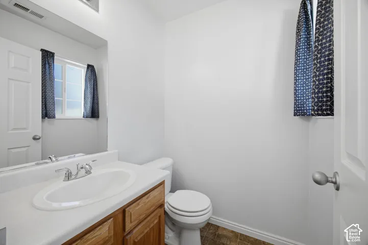 Bathroom featuring wood-finish cabinetry, a white countertop with an integrated oval sink, a chrome dual-handle faucet, a full-width mirror, and a single-pane window