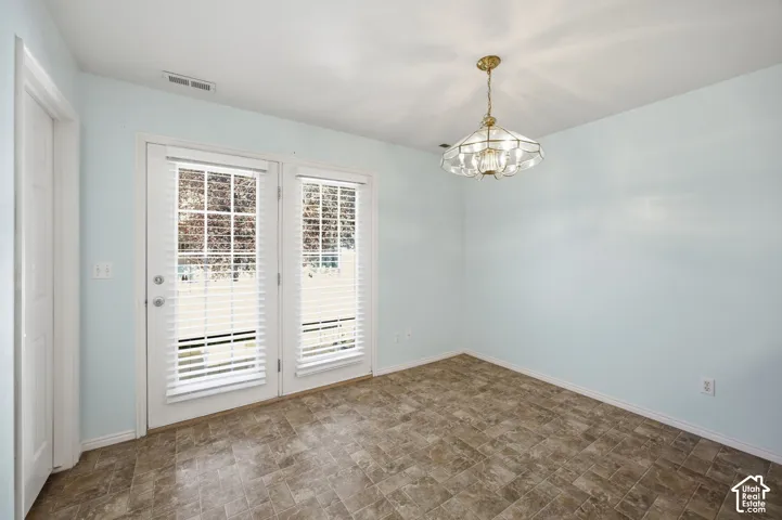Room featuring tile flooring, glass-paned door, coordinated window, and decorative pendant light fixture