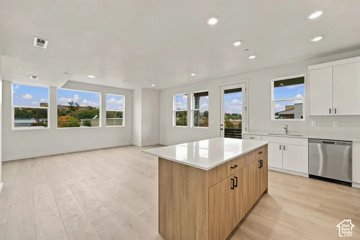 Kitchen featuring a center island with a stone countertop, wood-finish cabinetry, stainless steel dishwasher, recessed lighting, and wood-finish flooring