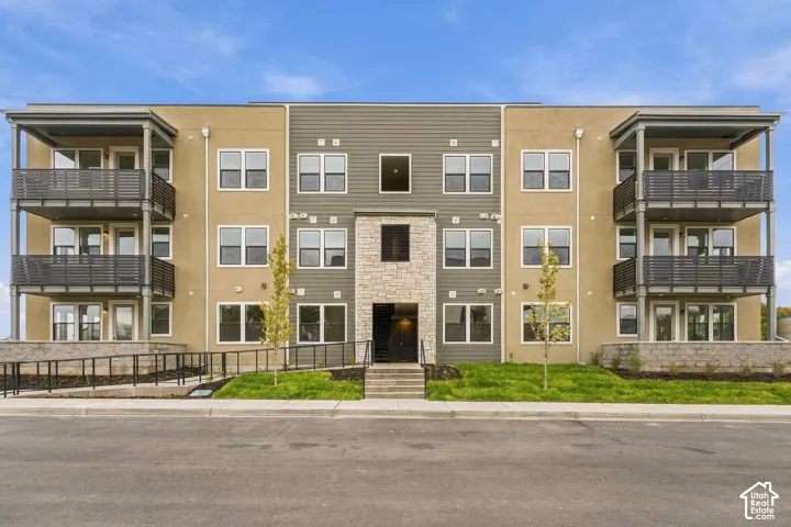 Multi-story exterior featuring a mix of stucco and horizontal siding, stacked private balconies with metal railings, and a central stone facade entry