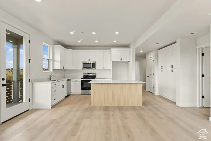 Kitchen featuring white shaker-style cabinetry, quartz countertops, a wood-finish island, recessed lighting, and wood-finish flooring