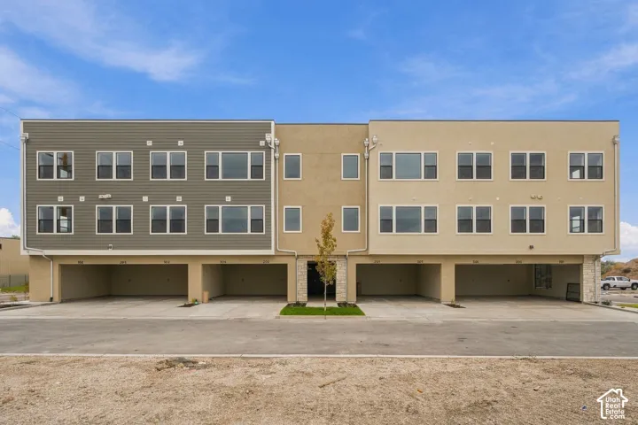 Contemporary multi-story exterior featuring a mix of horizontal lap siding and smooth-finish stucco, stone veneer accents, multi-pane windows, and integrated covered parking bays