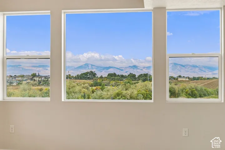 Three expansive picture windows featuring white frames and a mountainous landscape background
