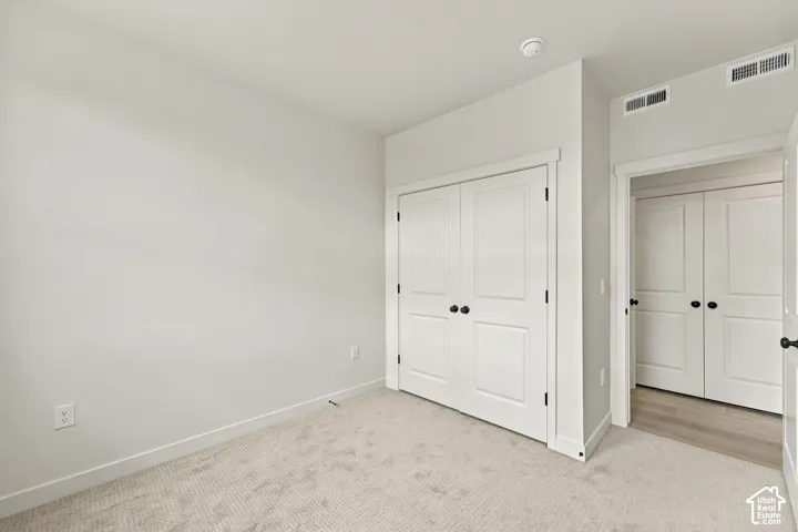 Neutral-toned interior featuring wall-to-wall carpeting, double-door reach-in closet, and matte black door hardware