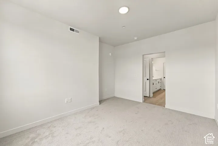 Neutral-toned wall-to-wall carpeting, crisp white walls, and recessed ceiling lighting