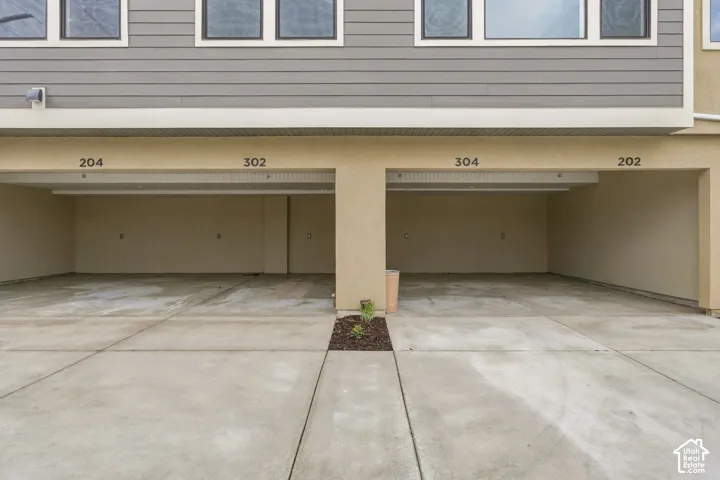 Covered parking area featuring dual tandem bays with concrete flooring, stucco exterior finish, and horizontal lap siding