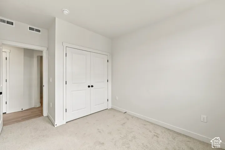 Neutral wall color, carpeted flooring, and double-door closet with matte black hardware
