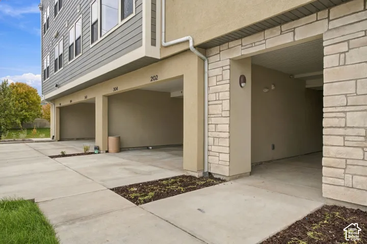 Covered parking area featuring stone masonry accents, horizontal lap siding, and concrete pavement