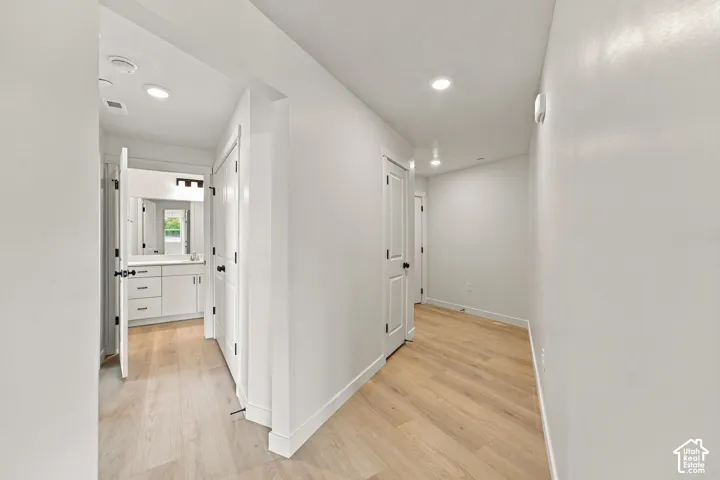 Hallway featuring wood-finish flooring, recessed lighting, and white paneled doors