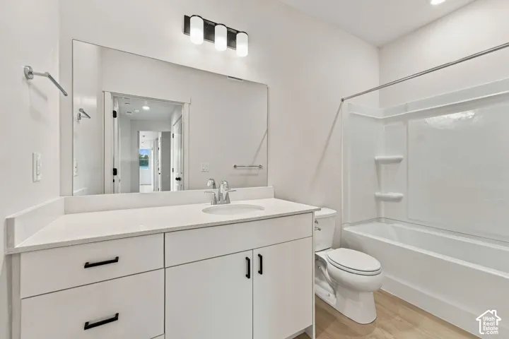 Bathroom featuring a vanity with a white countertop, undermount sink, matte black hardware, a wall-to-wall mirror, and a tub-shower combination with integrated shelving