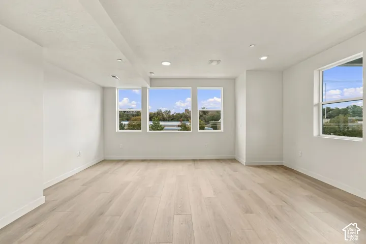 Neutral interior featuring wood-finish flooring, recessed lighting, and multiple windows