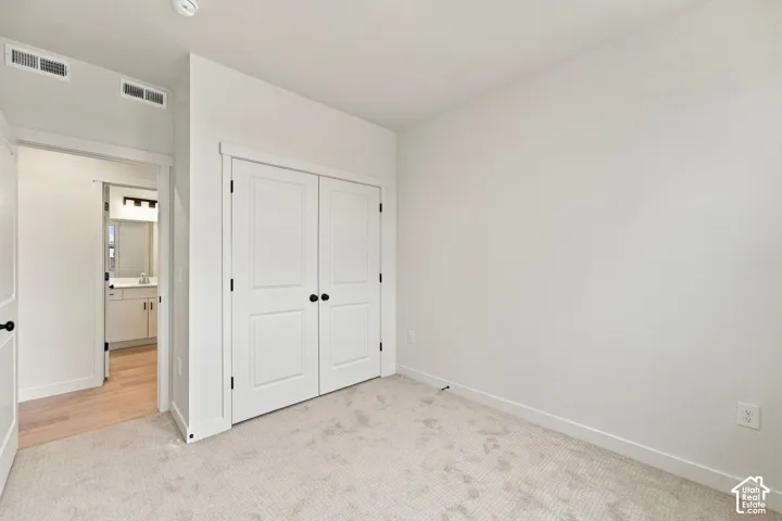 Neutral-toned interior space featuring wall-to-wall carpeting, dual-panel closet doors with matte black hardware, and smooth interior doors