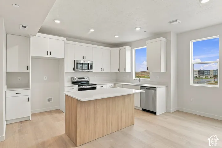 Kitchen featuring white cabinetry, wood-finish island, quartz countertops, stainless steel appliances, and recessed lighting