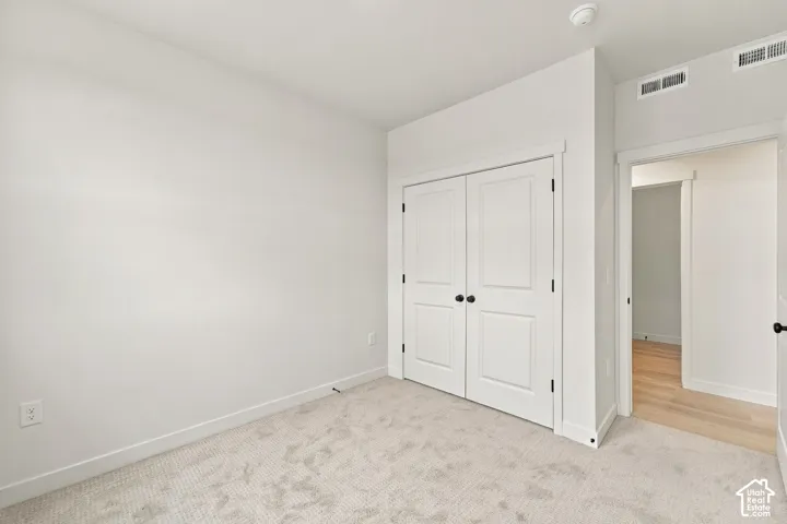 Neutral interior featuring wall-to-wall carpeting and double-panel closet doors with matte black hardware
