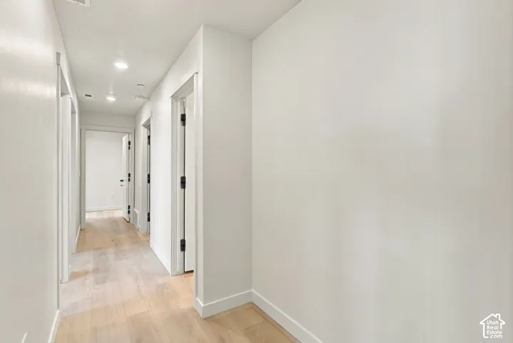 Interior hallway featuring wood-finish flooring, recessed lighting, and crisp white wall finishes