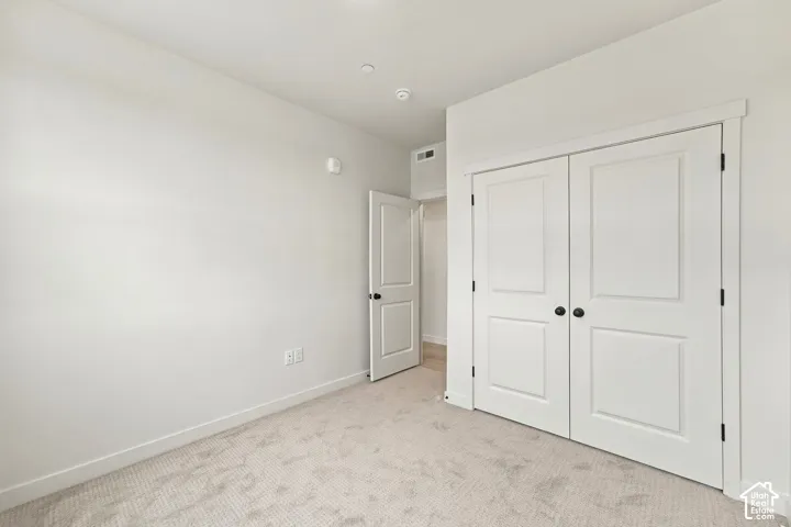 Neutral-toned interior space featuring wall-to-wall carpeting, dual-panel closet doors, and single-panel interior doors with matte black hardware