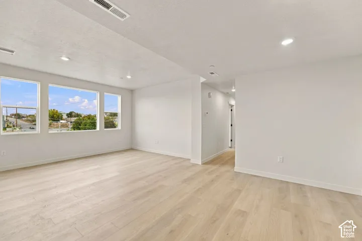 Open-concept interior featuring wood-finish flooring, recessed lighting, and large picture windows providing natural light