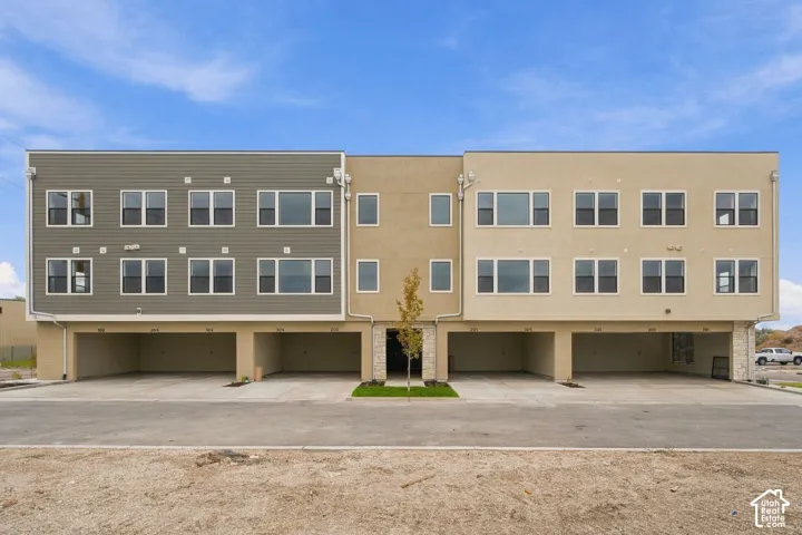 Multi-level exterior featuring horizontal siding, smooth stucco finish, stone veneer accents, and ground-level covered parking