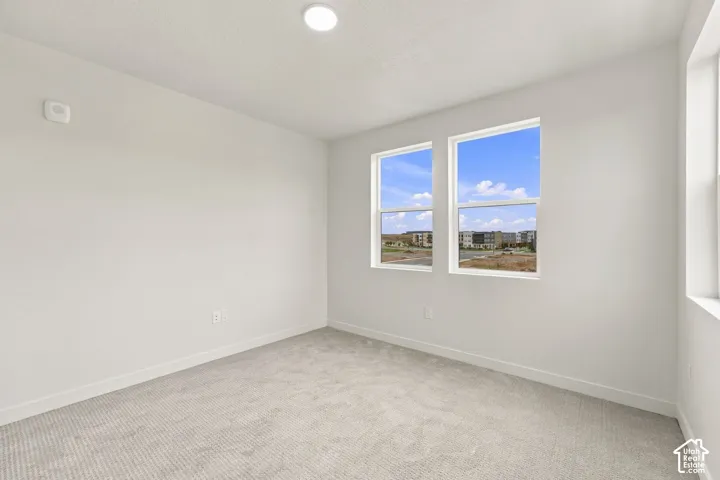 Neutral-toned interior room featuring wall-to-wall carpeting, dual-pane windows, and a ceiling-mounted light fixture