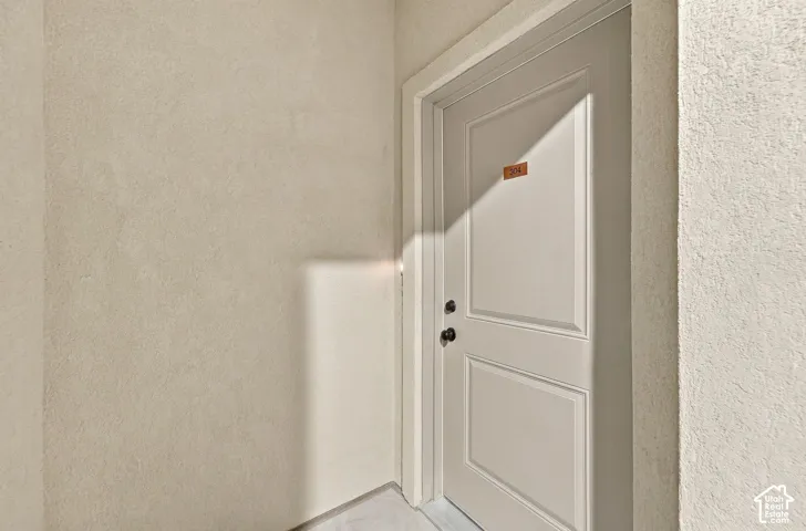 Neutral-toned interior entry door featuring a two-panel design, matte black hardware, and textured wall finish